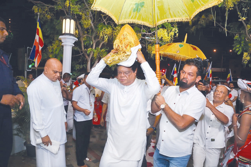 Transport, Highways and Mass Media Minister Dr. Bandula Gunawardena carrying the relics casket prior to the commencement of the all-night Pirith chanting ceremony.